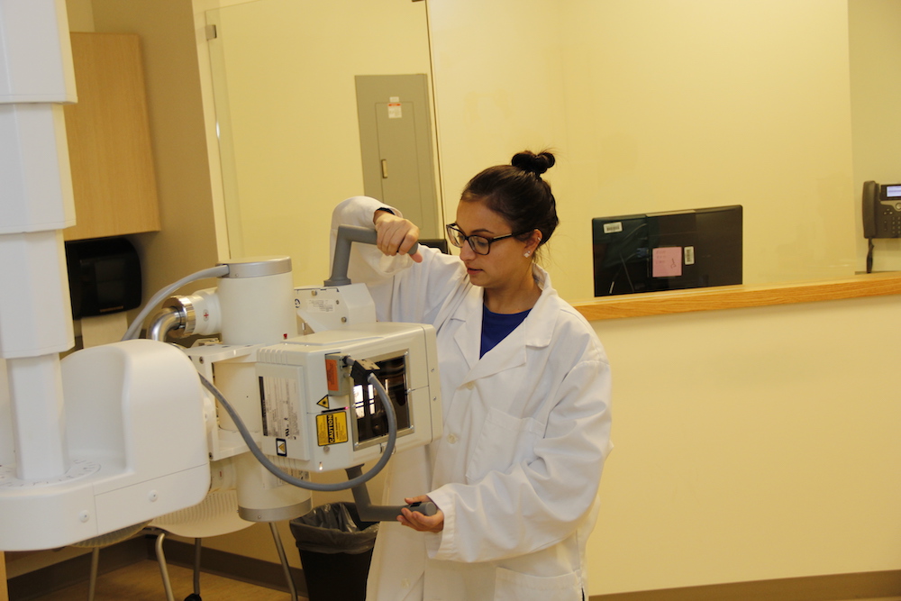 A female radiologic technology student uses the imaging machine